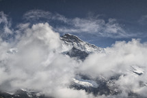 clouds over a snow covered mountain peak 