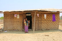 mother holding her children outside a small rural home 