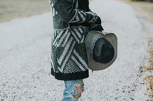 a woman in a sweater holding a hat 