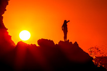 silhouette of a woman stretching on a mountain under a vibrant sky at sunset 