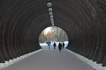 People walking through wooden tunnel .