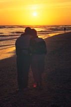 a couple snuggling on a beach at sunset 