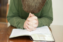 a man praying over the pages of a Bible 