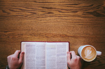 man reading a Bible and a mug of coffee 