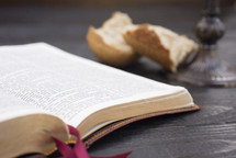an open Bible, bread, and chalice for communion 