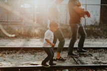 a young family walking on railroad tracks outdoors 