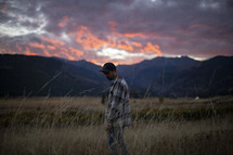 a man standing in a field at sunset 