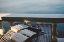 open Bible, journal, pen, phone, and watch on a table outdoors 