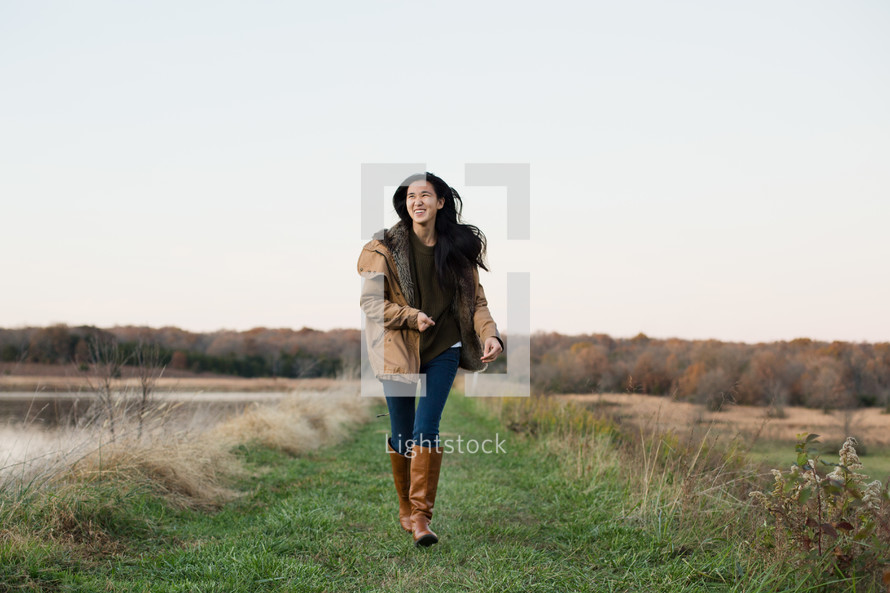 young woman walking in a coat and boots outdoors 