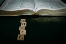 open Bible and the word grief in scrabble pieces 