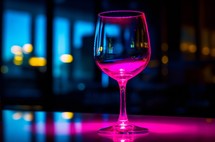 Close up of a wineglass with pink neon light reflection
