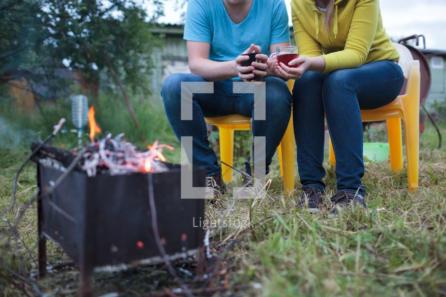 Couple with tea cups in hands near the smouldering fire