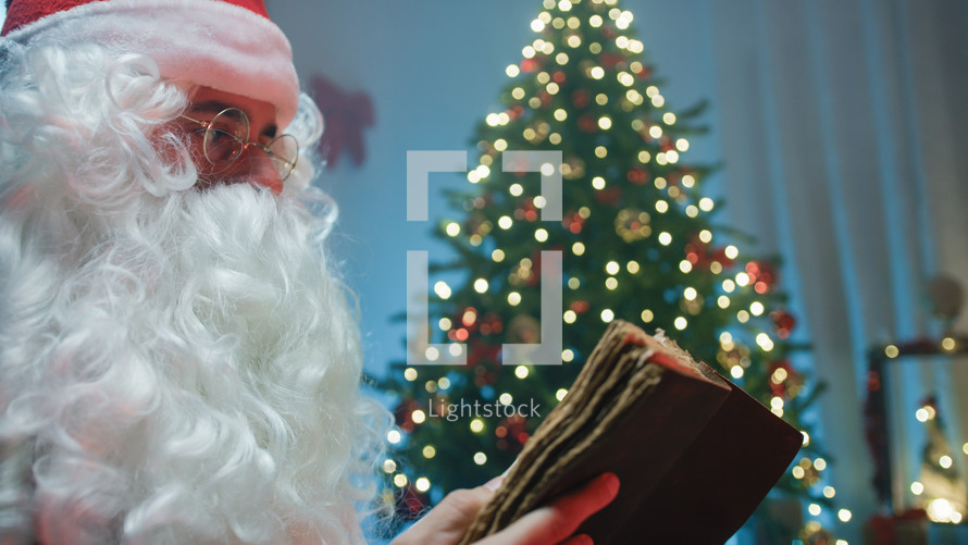 Santa Claus reading under the Christmas tree