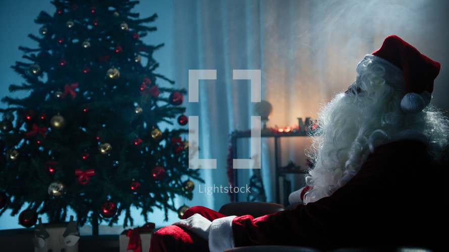 Santa Claus looks at unlit Christmas tree