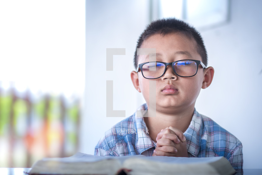 a child praying over a Bible 