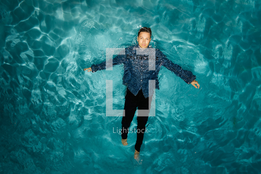 man in dress clothes floating in a water 