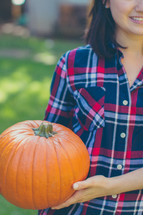 woman holding an orange pumpkin 