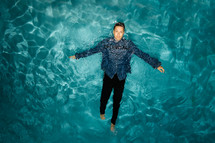 man in dress clothes floating in a water 
