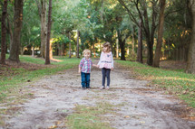 brother and sister walking on a dirt road 