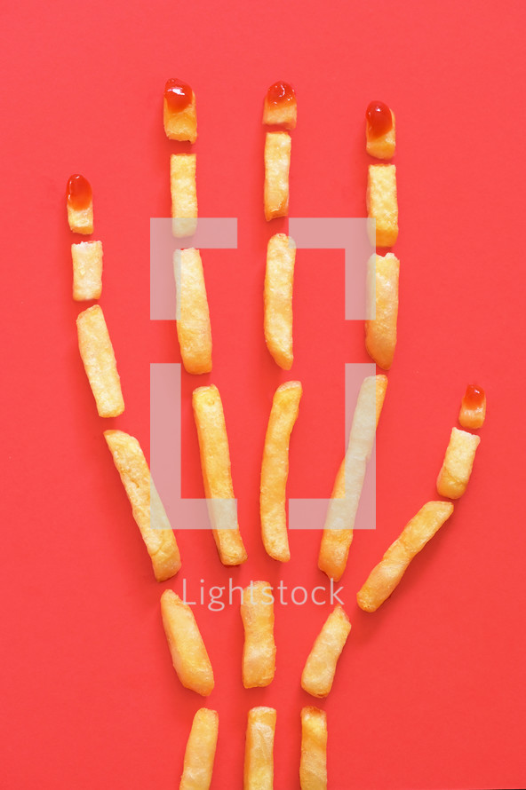 Human Hand Concept With French Fries on Red Background