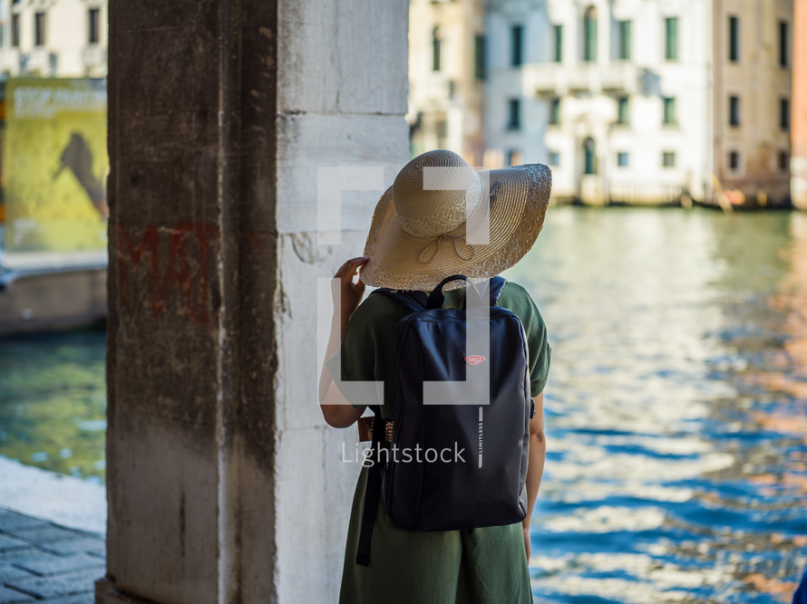 a woman in a sunhat looking out at a channel in Venice 