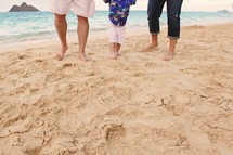 Father, mother and young son walking on the beach.