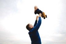 a father holding his infant son in the air 