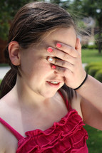 teen girl covering her eyes with her hand 