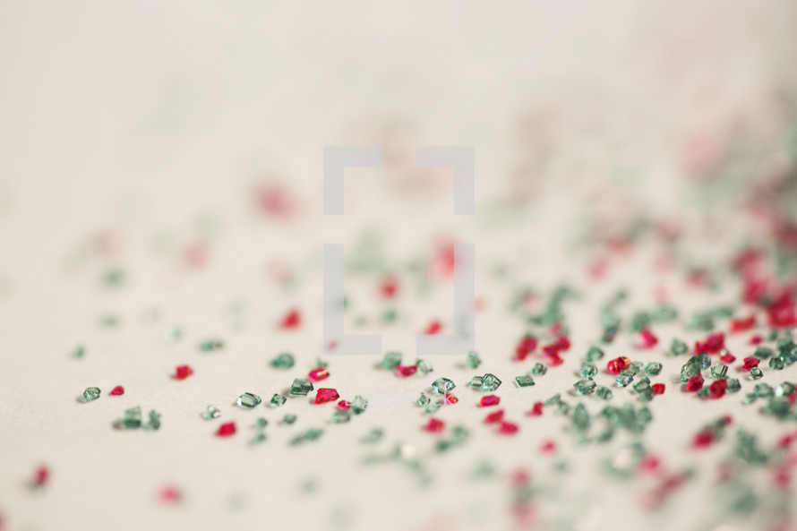 Small pieces of green and red glass scattered on a white background.