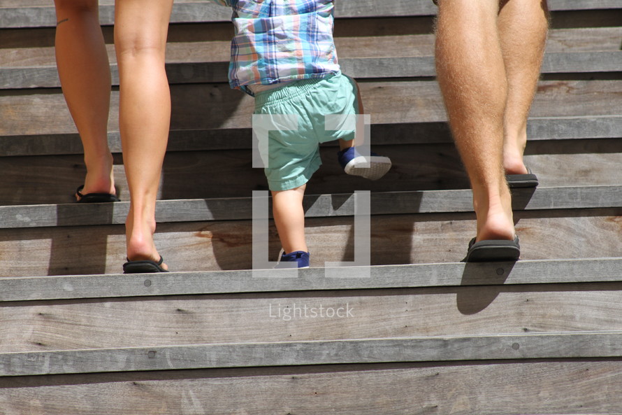 a mother and father walking up a flight of stairs with their toddler son 