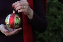 a woman holding a Christmas ornament 