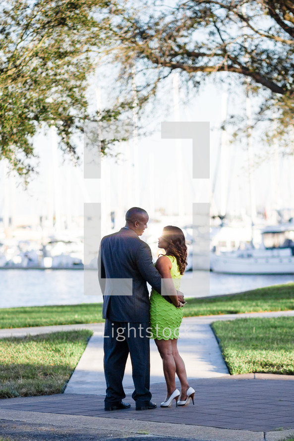 couple standing looking out at boats on the water 
