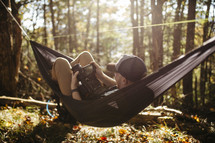 man with a camera resting in a hammock in a forest 