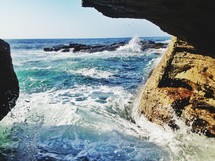 waves crashing into rocks at the mouth of a sea cave