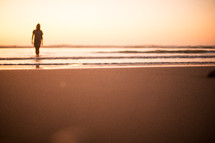 a woman walking on a beach at sunset 