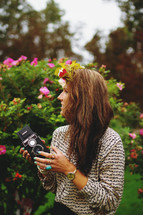 a woman with flowers in her hair holding a vintage camera 