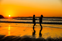 friends dancing in celebration on a beach at sunset 
