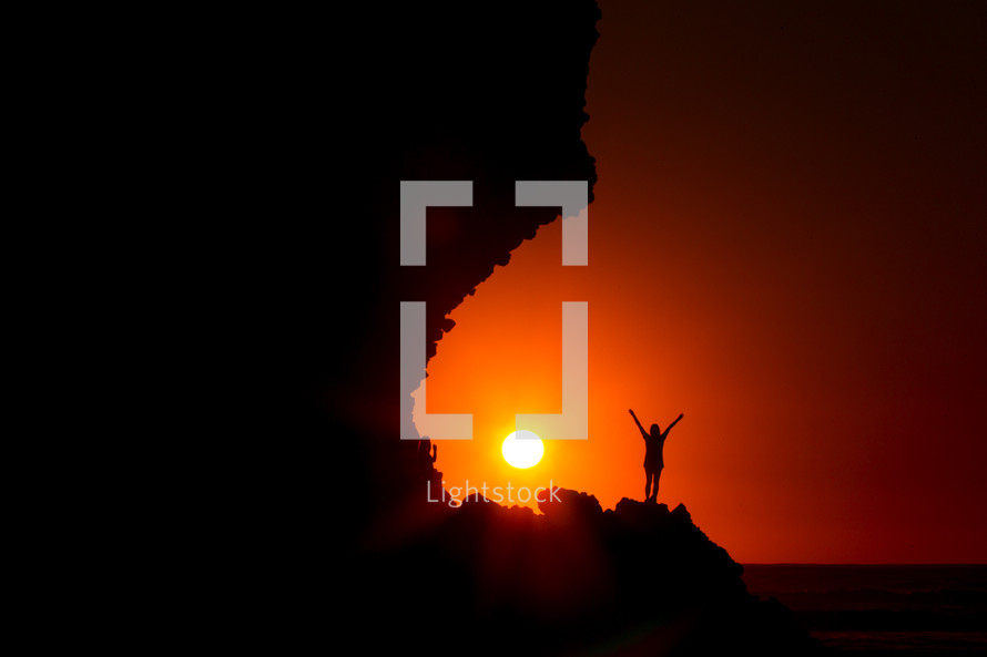 silhouette of a woman stretching on a mountaintop at sunset 