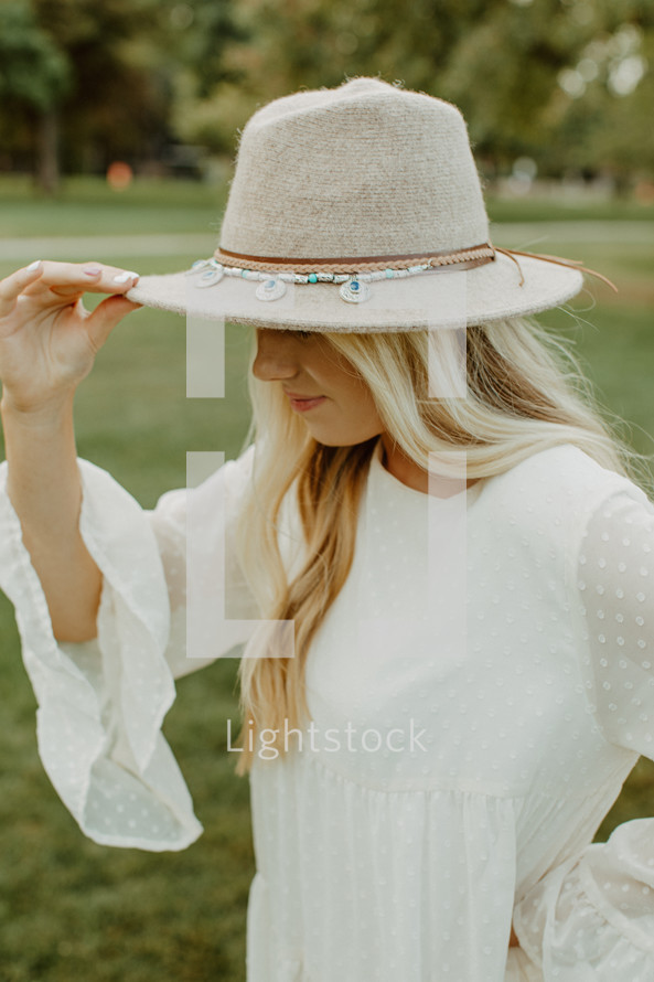 a young woman in a hat standing outdoors 