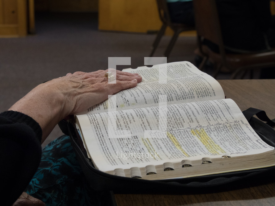 an elderly woman reading a Bible 