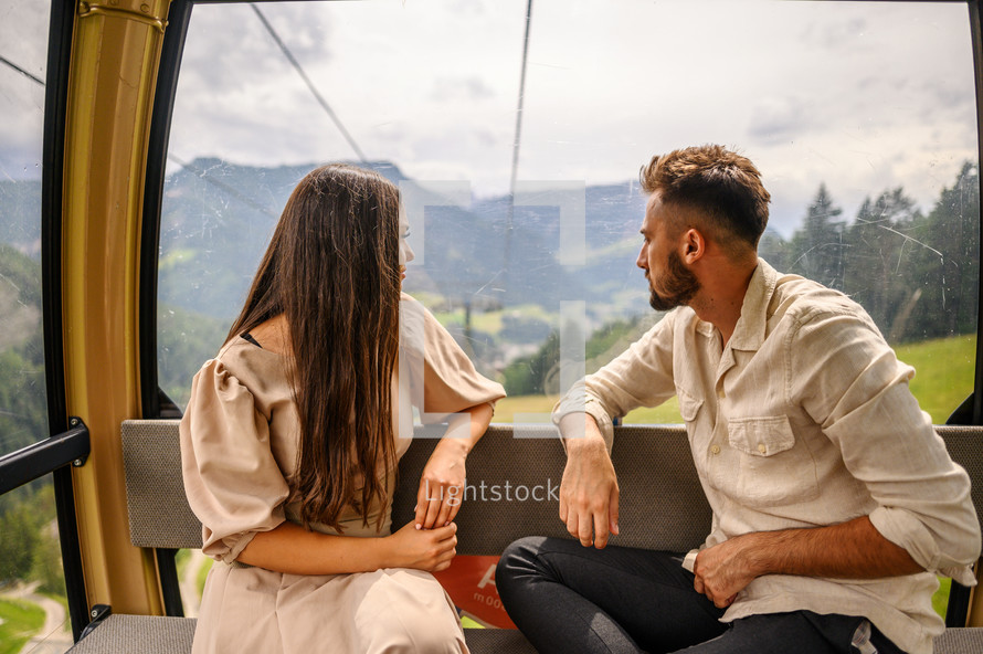 a couple riding in a lift over a mountaintop 