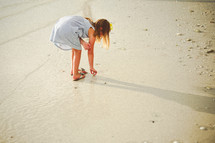a girl in a sundress walking on a beach 