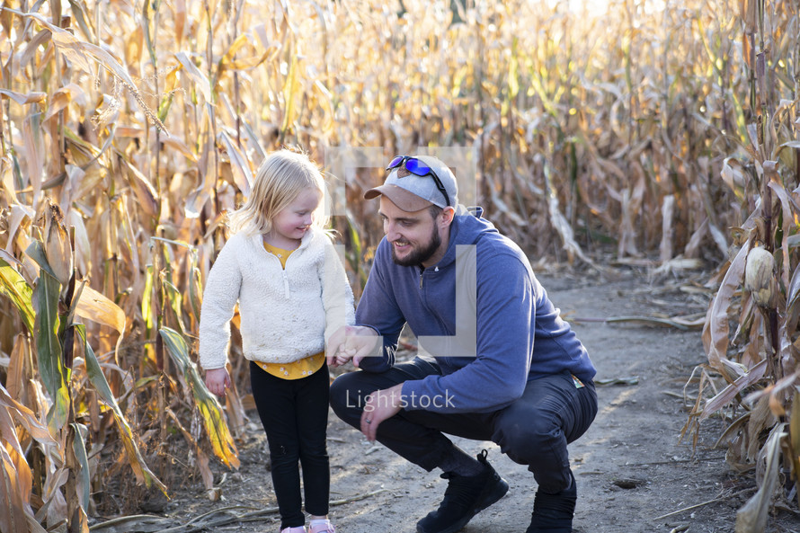 Man and daughter in corn stalks in the fall