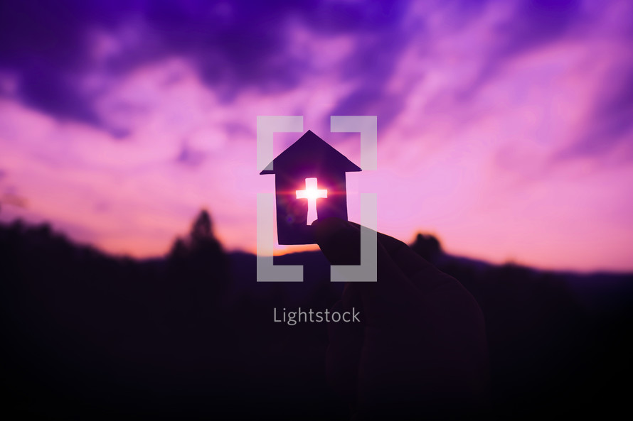 Hand holding home cross shapes, with light of sunset purple color background, christian silhouette concept