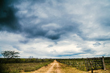 rain clouds over a rural dirt road 