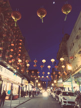 hanging paper lanterns over a street at night 
