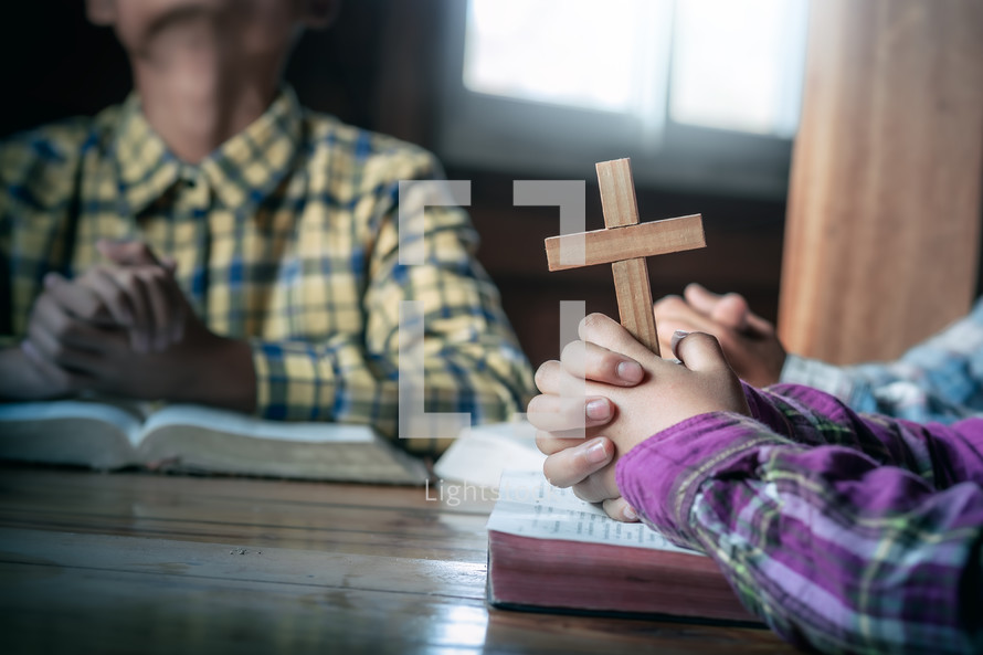 Children group Bible study praying holding a cross