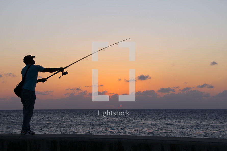 Man fishing on a beach at sunset 