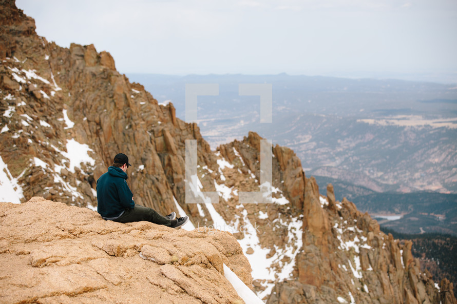man sitting on top of a mountain 