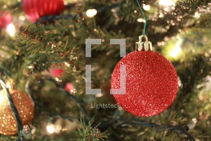 red glittery ornaments hanging on a Christmas tree 